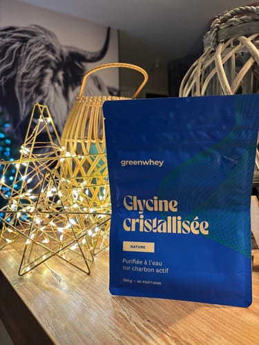 La Glycine cristallisée d'un client dans son sachet bleu, posée sur une surface en bois à côté d'une étoile lumineuse.