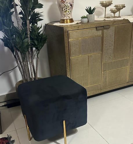 Customer's black velvet Gela Stool with gold legs placed on a tiled floor next to a gold cabinet.