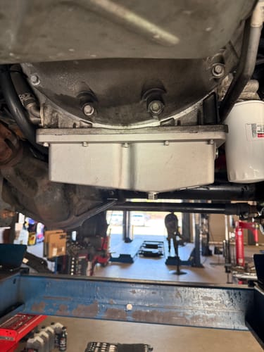 Customer's silver SPE Motorsport Oil Pan installed on the underside of a vehicle on a lift.