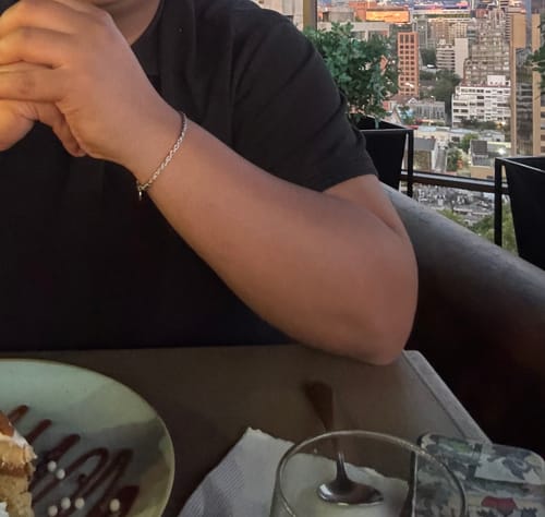 Primer plano de un cliente luciendo la Pulsera Rope 3mm en su muñeca en una terraza.