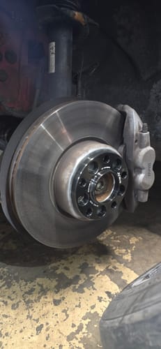 Customer's black hubcentric wheel spacer installed on a BMW's brake disc assembly in a garage setting.