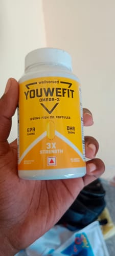 Customer holding the white and yellow bottle of YouWeFit Omega-3 Fish Oil capsules.