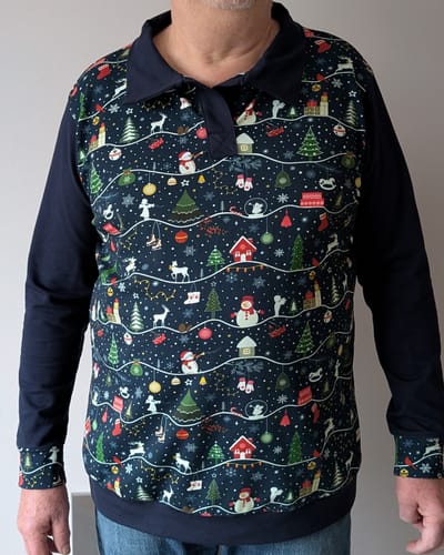 Customer wearing a Christmas jumper made from the Snowy Christmas fabric, with solid navy sleeves, collar, and hem.
