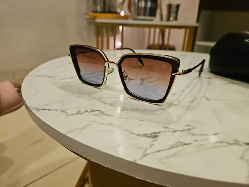 Customer's Cateye Sunglasses with golden frames and gradient lenses on a table.
