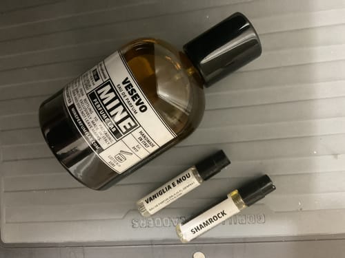 Il cliente mostra i campioni di profumo "Vaniglia e Mou" e "Shamrock" del set, accanto a un flacone di profumo "Vesevo".