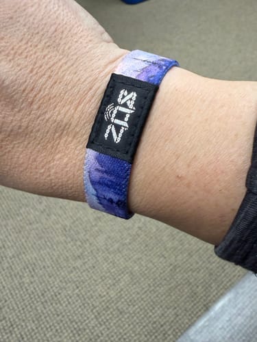 Close-up of a customer wearing the purple and blue Live By Faith Bible Verse Bracelet on their wrist.