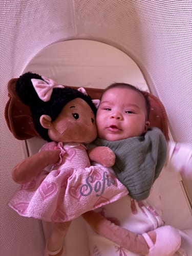 Customer's Personalized Sweetheart Girl doll, customized with the name 'Sofia', lying next to a baby in a crib.