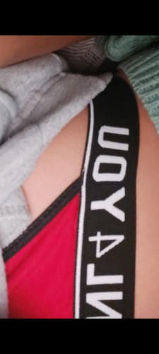 Close-up of a reviewer wearing the red lingerie, showing the thick black branded waistband at their hip.