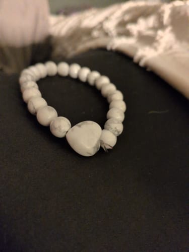 Customer's white beaded bracelet from the VIP Crystal Club, featuring a heart-shaped bead in the center.