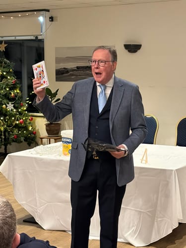 Reviewer performing The Five Card Opener magic trick, holding a jumbo playing card up for an audience.