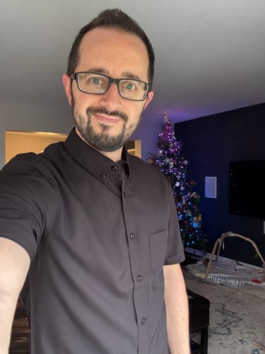 Reviewer showing the slim fit of the solid black KUNUFLEX short sleeve shirt.