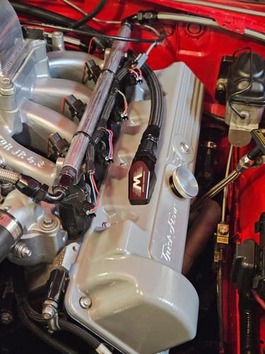 Customer's black Billet Valve Cover Breather installed on a silver valve cover in a car engine.