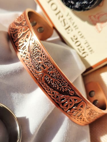 Reviewer's detailed copper Tree of Life cuff bracelet resting on a white cloth.