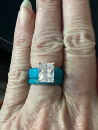Customer's hand wearing the turquoise silicone ring set, featuring a large emerald-cut stone on a matching band.