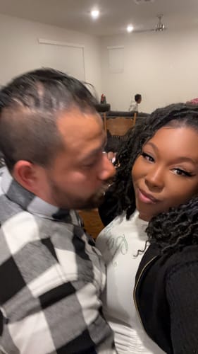 Customer taking a selfie with her husband, capturing his happy reaction to their upgraded melody.