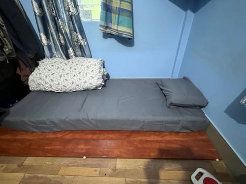 Customer's Flo Mattress Ergo on a bed frame, covered with a grey sheet and matching pillow.