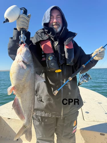 Customer on a boat holding a large fish and their blue Waterloo Salinity spinning rod.