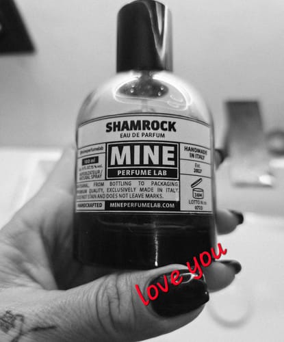 Recensore tiene in mano il suo profumo SHAMROCK in questa foto in bianco e nero.