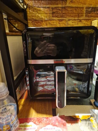 Client prezentând air fryer-ul negru și lucios Novio StonePro pe un blat de bucătărie.