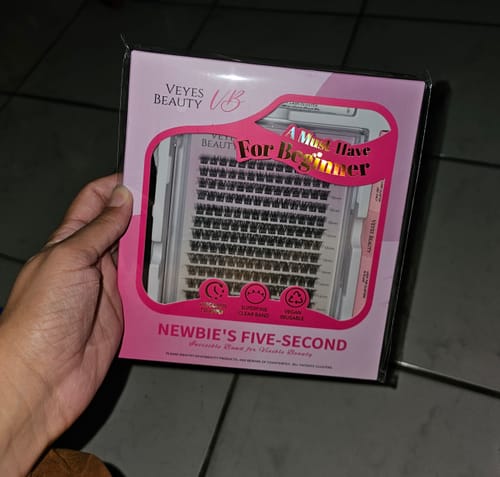 Customer holding the packaging for Dreamy lash clusters, which is pink and black.