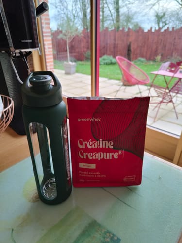 Avis d'un client montrant le sachet de Créatine Creapure® à côté d'une gourde verte sur une table.