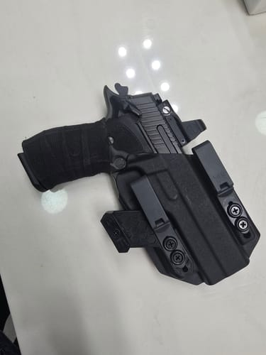 Customer's black XIPHOS V2 holster with a pistol, showing its clips and concealment claw on a table.