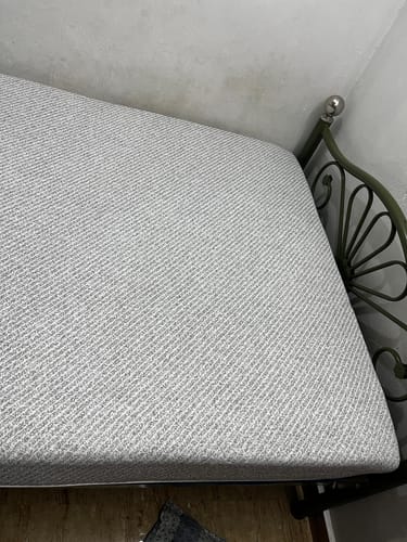 Close-up of a customer's Flo Anti-Gravity™ Latex Mattress, showing the grey textured cover on a metal bed frame.