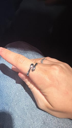 Customer wearing the silver Hug Ring on their index finger, seen on their hand against denim fabric.