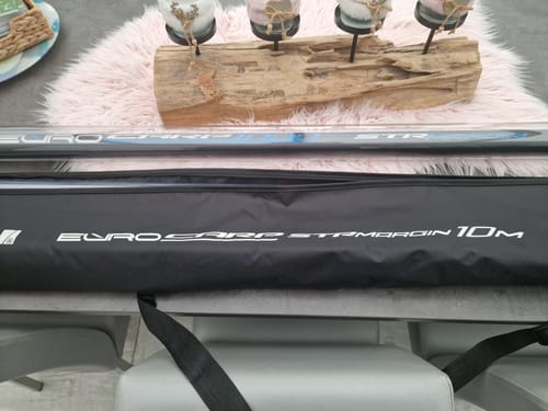 Klant toont de EURO CARP 1000 STR MARGIN hengel naast het bijbehorende zwarte foedraal op een tafel.