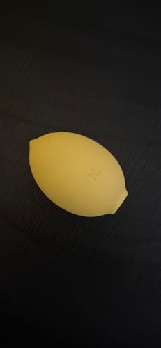Reviewer's yellow, lemon-shaped Lem massager resting on a dark surface.