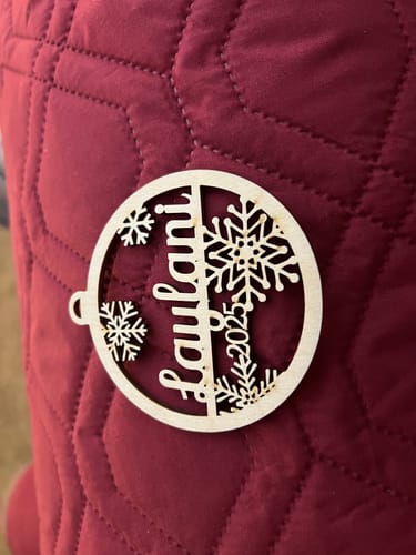 Customer's personalized birch wood ornament with the name "Laulani" and "2025" laser-cut into a snowflake design.