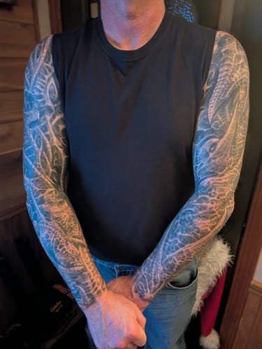 Customer showing vibrant, full-sleeve tattoos on both arms after using the F-Balm from the Tallowed Truth Starter Pack.