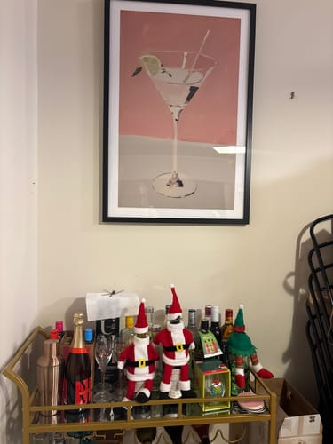 Customer's 'Martini on Pink' art print in a black frame, hanging above a home bar cart.