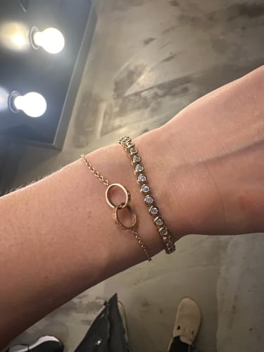 Customer's wrist wearing the shiny Classic Bezel Tennis Bracelet stacked with another delicate bracelet.