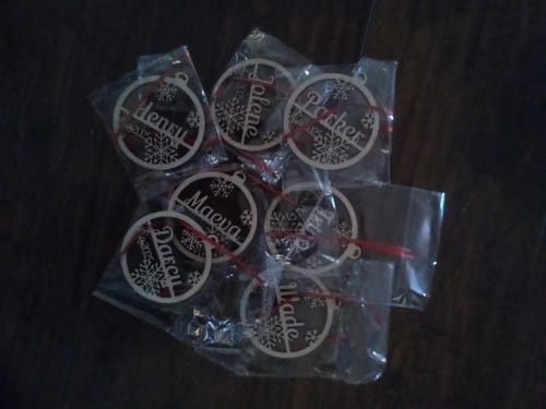 Customer's seven personalized wooden Christmas ornaments, each individually packaged with a red ribbon.