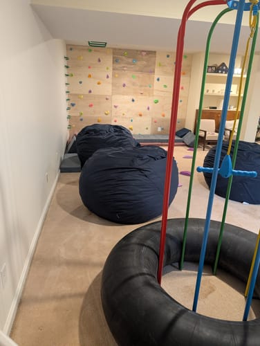 Partial view of a customer's colorful Jungle Jumparoo set up indoors in a large playroom.
