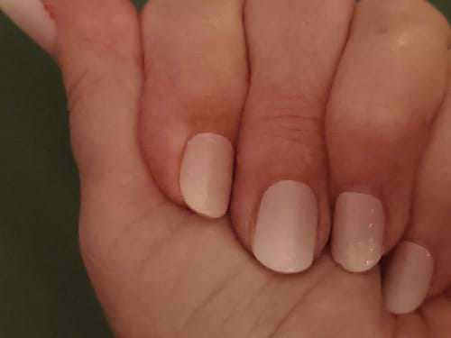 Rezensentin zeigt eine Nahaufnahme ihrer Maniküre mit den dezenten Babyboomer Nude Nagelfolien nach einer Woche.
