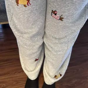 Customer showing a close-up of their grey Embroidered Pup Barrel Sweatpants, highlighting the embroidered dogs.