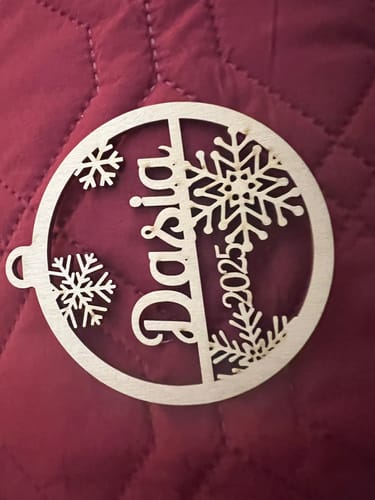 Customer's personalized birch wood ornament with the name "Dasia" and "2025" laser-cut into a snowflake design.