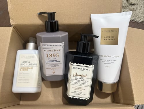 Recensent toont de Jardin Imperial Hand & Bodylotion in een witte tube, naast andere lotions in een doos.