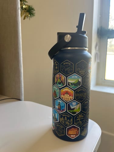 Reviewer's World Explorer Bottle with colorful destination stickers on a white desk.