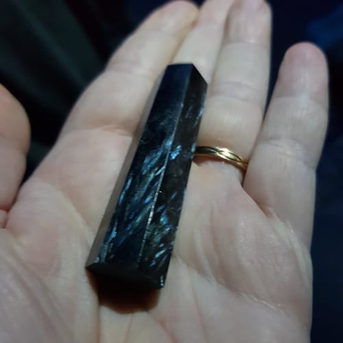 Un client tient une magnifique pointe d'astrophyllite dans le creux de sa main.