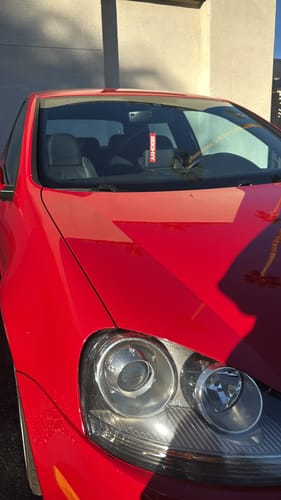 Customer's red 80Eighty air freshener hanging from the rearview mirror of a matching red car.