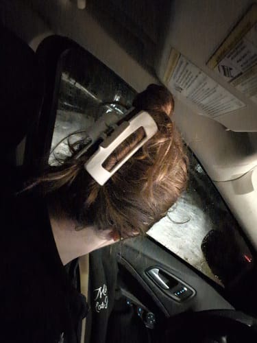 Customer's white cloud clip holding their brown hair in a bun while they sit in a car.