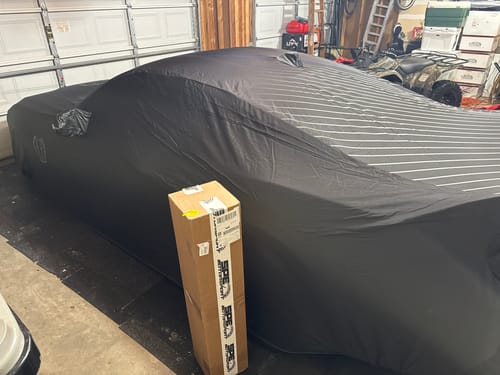 Customer's box containing the SPE Motorsport Exhaust X F1 Pipe, next to their covered Mustang in a garage.