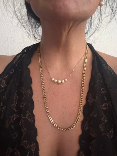 Una cliente luce la Cadena Miami Cuban Oro de 5mm combinada con un collar de perlas y un top de encaje.