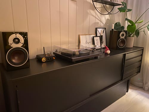 Anmelderens høyttaler, dekket med Walnut Deep kontaktplast, på en svart skjenk med en platespiller.
