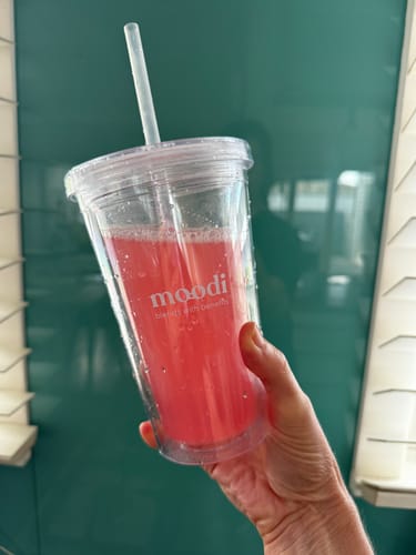 Customer holding the clear Blends with Benefits Tumbler filled with a pink drink.