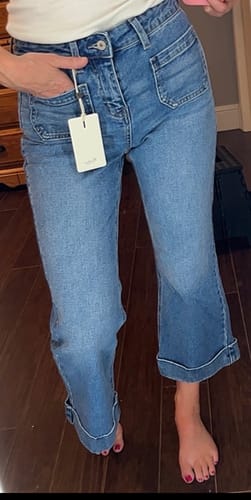 Reviewer showing the fit of the mid-wash Kancan Angelina Crop Flare Jeans with front patch pockets and cuffed hems.