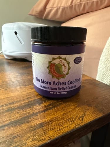 Customer's purple jar of No More Aches Cooling cream sitting on a wooden nightstand.